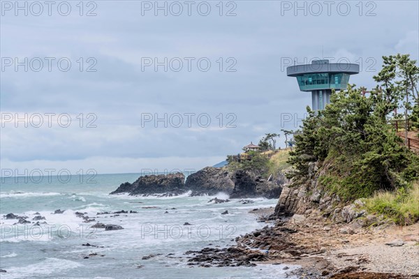 An observation tower overlooks a rocky coastline with crashing ocean waves, in Ulsan, South Korea, Asia