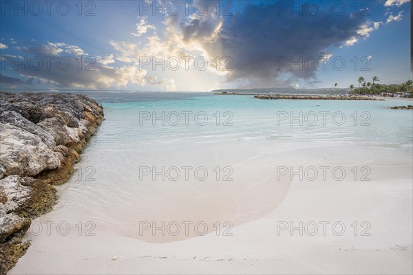 Caribbean dream beach with palm trees, white sandy beach and turquoise-coloured, crystal-clear water in the sea. Shallow bay at sunset. Plage de Sainte Anne, Grande Terre, Guadeloupe, French Antilles, North America