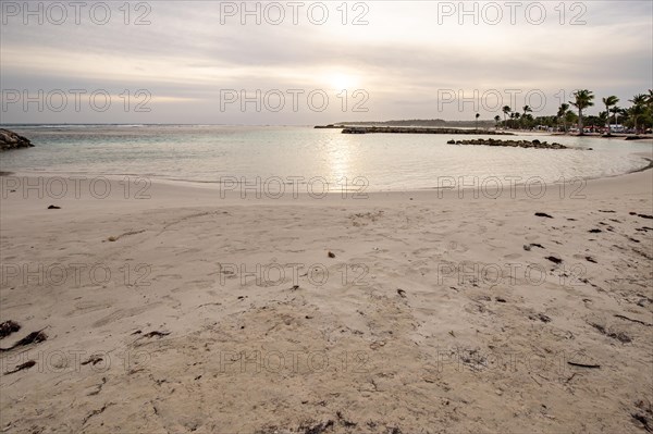 Caribbean dream beach with palm trees, white sandy beach and turquoise-coloured, crystal-clear water in the sea. Shallow bay at sunset. Plage de Sainte Anne, Grande Terre, Guadeloupe, French Antilles, North America