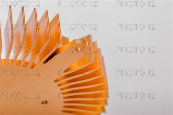 Closeup of fins and mounting flange on round copper computer heat sink on white background