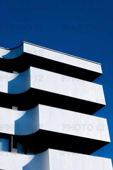 Beautiful Modern Concrete Design Building with Metal Balcony Against Blue Clear Sky in Switzerland