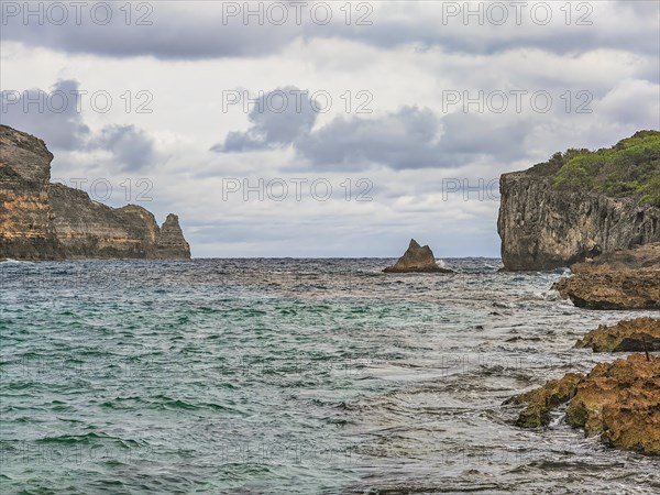Rocky coast, long bay by the sea at sunset. Dangerous view of the Caribbean Sea. Tropical climate on a cloudy day in La Porte d'Enfer, Grande Terre, Guadeloupe, French Antilles, North America
