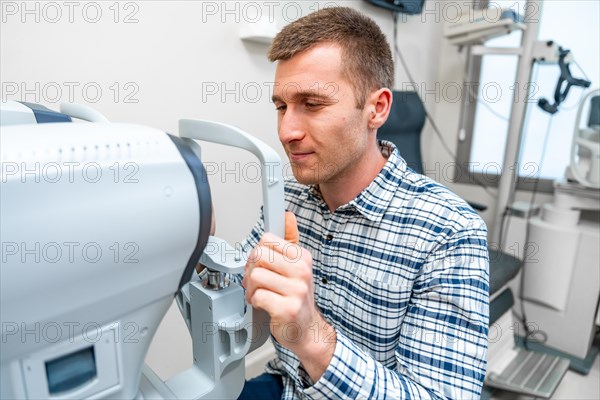 Man holding the handles of a eye scanner in an ophthalmology clinic