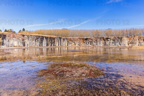 Old disused limestone quarry with water reflections on the ground at springtime