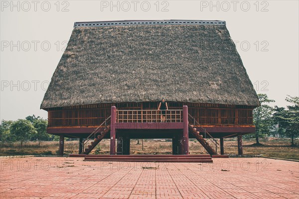 A tourist exploring a traditional architecture of a Bahnar ethnic stilt house or Rong House in Pleiku countryside, Vietnam, Asia