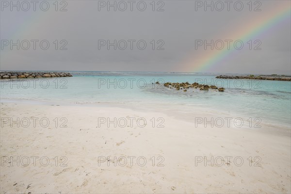 Caribbean dream beach with palm trees, white sandy beach and turquoise-coloured, crystal-clear water in the sea. Shallow bay with rainbow. Plage de Sainte Anne, Grande Terre, Guadeloupe, French Antilles, North America