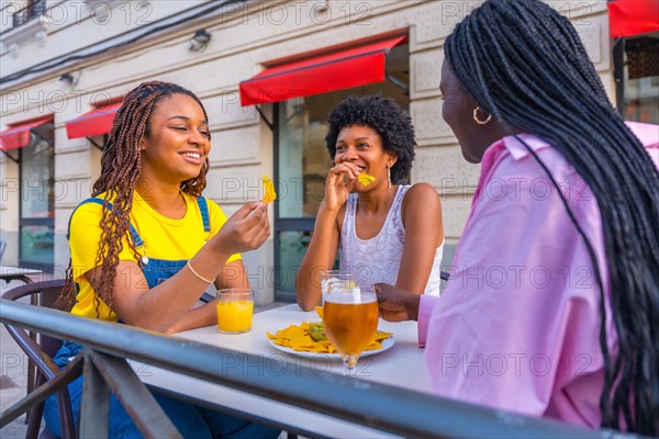 African young woman eating fast food and drinking beer in a sidewalk restaurant