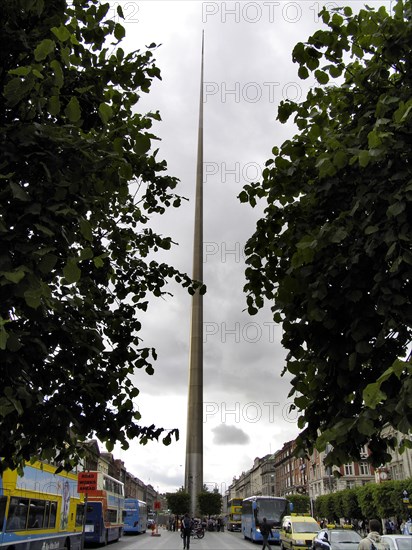 A slender monument rises between green trees under a cloudy sky Ireland's capital Dublin