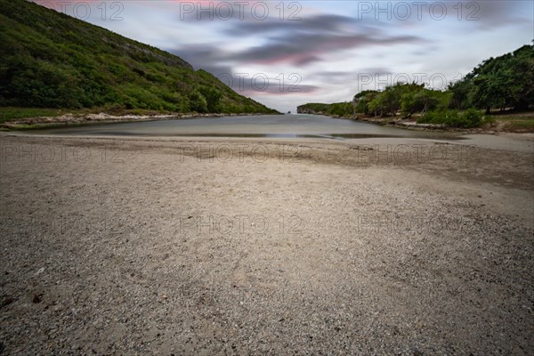 Rocky coast, long bay by the sea at sunset. Dangerous view of the Caribbean Sea. Tropical climate at sunset in La Porte d'Enfer, Grande Terre, Guadeloupe, French Antilles, North America