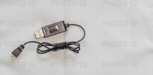 A coiled USB cable with metal accents on a white background, in South Korea