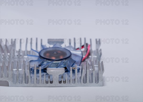 Closeup of aluminum heat sink and blue plastic fan assembly on white background