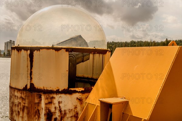 Searchlight under Plexiglas dome mounted on side of bridge under cloudy sky in South Korea