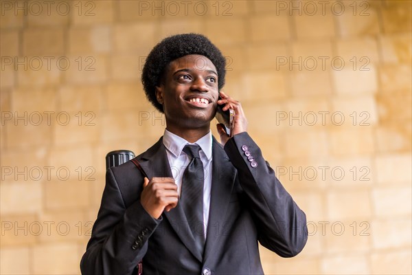 Low angle view portrait of a proud young african architect talking to the mobile and smiling outdoors