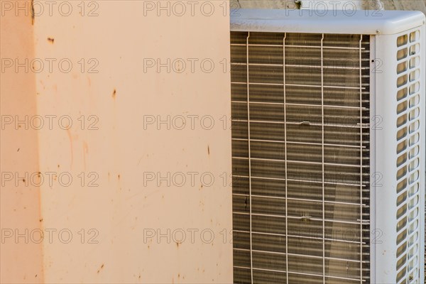 Closeup of air conditioner condenser unit behind a pinkish colored wall in South Korea
