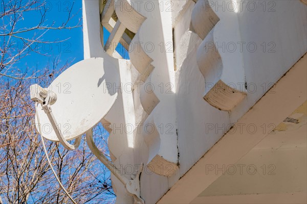 Satellite dish mounted on white architectural structure with clear blue sky in the background, in South Korea