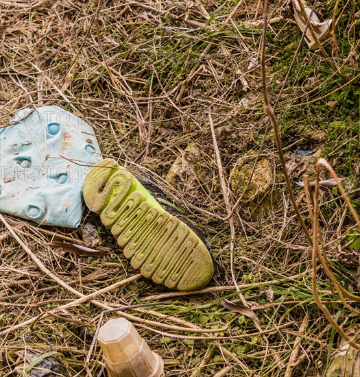 Discarded shoe amidst plastic litter on the ground, showing environmental damage, in South Korea