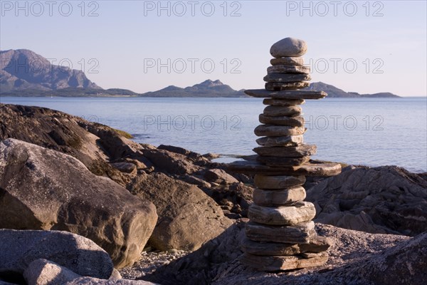 Balanced pile of stones on a quiet coastal landscape with a mountain panorama in the background Steinmann Lofoten Norway