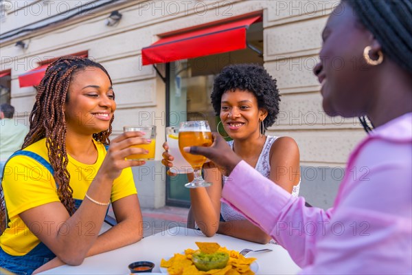 African women toasting on an outdoor terrace while eating fast food and nachos