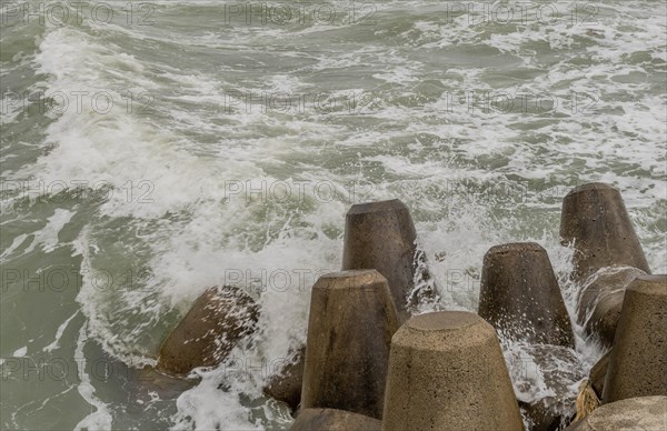 Choppy ocean waves crash against erosion control concrete blocks on a cloudy day, in Ulsan, South Korea, Asia
