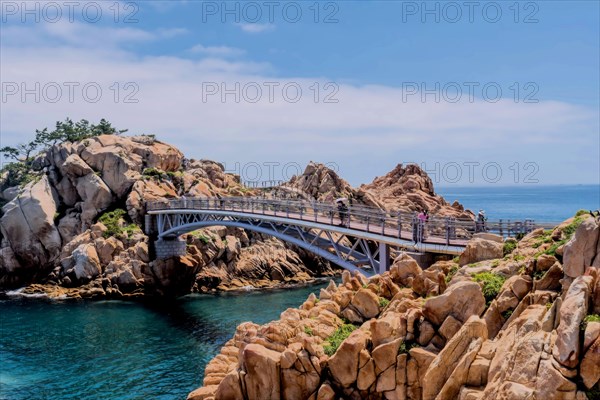A bridge spanning over rocks by the sea with a clear blue sky, in Ulsan, South Korea, Asia