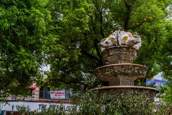 A detailed fountain set against urban greenery and store facades, in Chiang Mai, Thailand, Asia