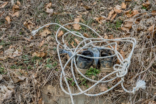 Old shoes tied with a rope lying on leaf-strewn ground, in South Korea