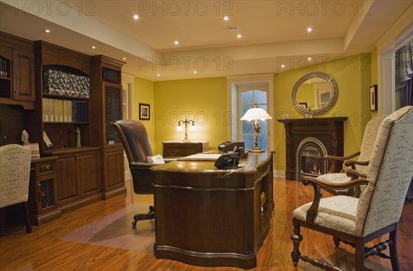 Wooden desk, high back chairs and wall unit in basement home office inside elegant style home, Quebec, Canada, North America