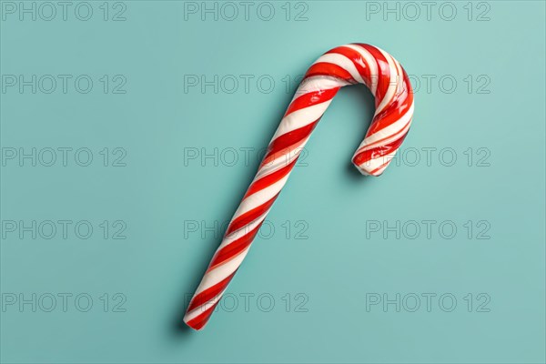 Top view of single red and white striped Candy Cane on blue background. KI generiert, generiert, AI generated