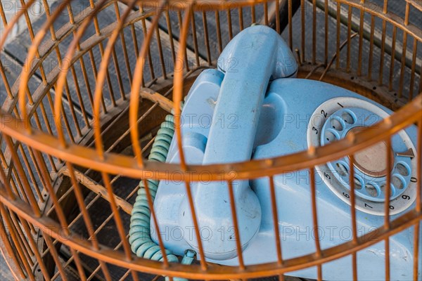 Old style rotary phone sitting in birdcage sitting outside on wooden step in Seoul, South Korea, Asia