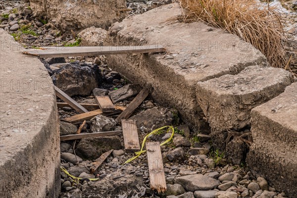 Damaged small concrete bridge with wooden planks over a stream bed, in South Korea