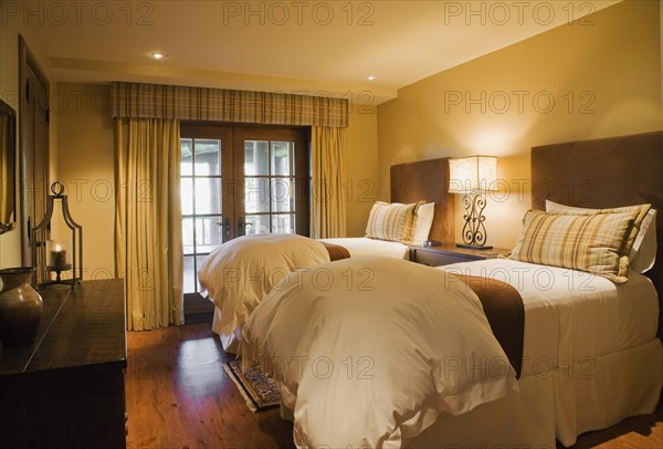 Guest bedroom with single beds and wooden dresser in basement inside luxurious log cabin home, Quebec, Canada, North America