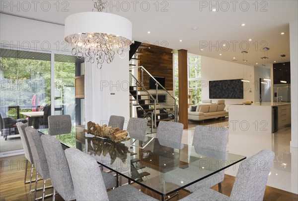Glass dining table with gray upholstered high back chairs in dining room inside luxurious home, Quebec, Canada, North America