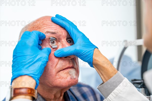 Ophthalmologist applying an eye opener on a senior patient before an innovative treatment for glaucoma