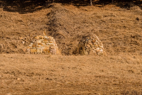 Two pyramid shaped rock structures in field of brown grass at foot of hillside in Boeun, South Korea, Asia