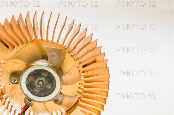 Closeup of round copper heat sink and plastic fan assembly on white background