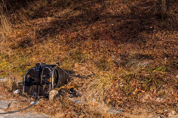 Pieces of broken office chair lies abandoned at the roadside with dry grass, in South Korea