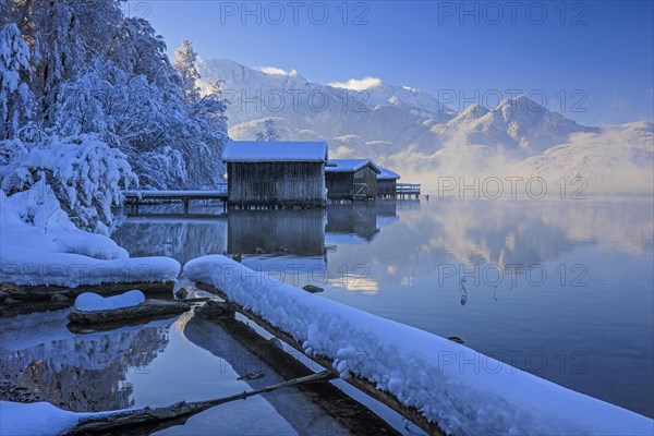 Morning atmosphere at mountain lake in front of mountains, boat huts, shore, winter, snow, reflection, Lake Kochel, Alpine foothills, Bavaria, Germany, Europe