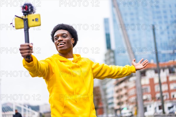 Happy african young streamer smiling at camera while broadcasting using phone in the city