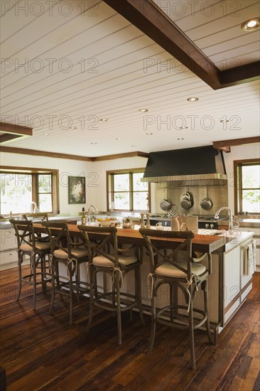 Country style kitchen with island and rustic wooden high chairs inside New Hampton style home, Quebec, Canada, North America