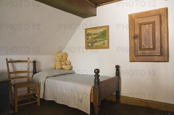 Antique wooden weaved seat chair and single four-poster bed in bedroom on upstairs floor inside old 1785 home, Quebec, Canada, North America