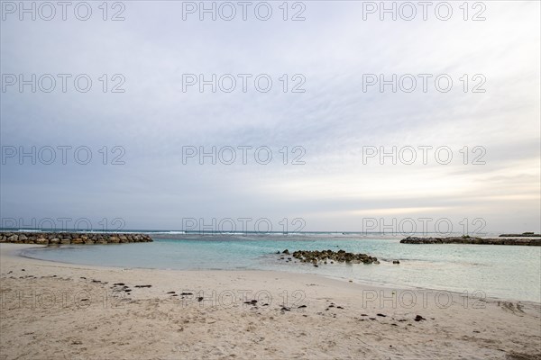 Caribbean dream beach with palm trees, white sandy beach and turquoise-coloured, crystal-clear water in the sea. Shallow bay on a cloudy day. Plage de Sainte Anne, Grande Terre, Guadeloupe, French Antilles, North America