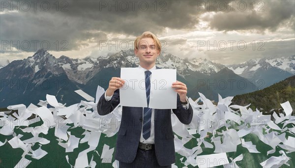 A man in a suit holds up a leaf in front of dramatic mountains and a cloudy sky, symbolising bureaucracy, AI generated, AI generated