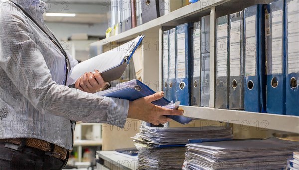 A woman works efficiently in the archive sorting files and paperwork, symbolism bureaucracy, AI generated, AI generated