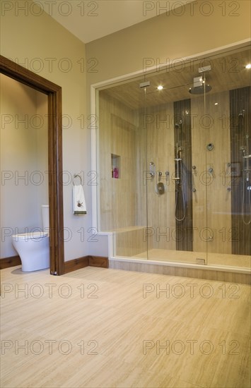 Main bathroom with double steam glass shower stall and toilet room in extension inside luxurious log cabin home, Quebec, Canada, North America