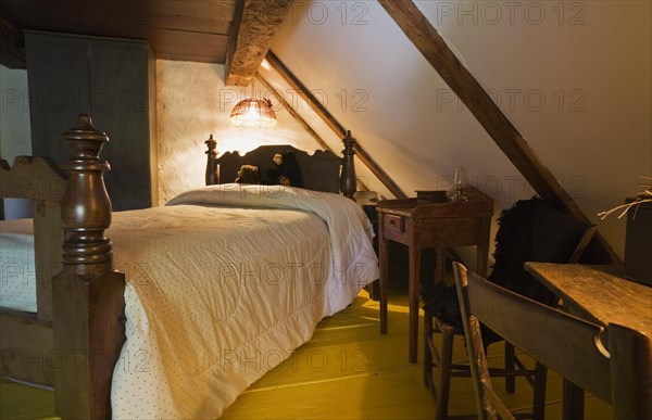 Antique wooden four-poster single bed and armoire in bedroom on upstairs floor inside old 1785 home, Quebec, Canada, North America