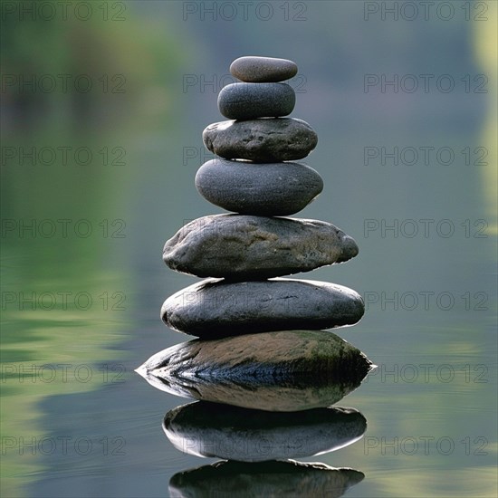 Smooth stones stacked in a balanced tower reflected in tranquil water, image depicting relaxation, recreation, serenity, naturalness, meditation, enjoyment concepts, AI generated