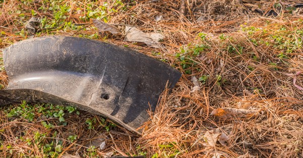 A brittle plastic car part is abandoned outdoors on grass, contributing to pollution, in South Korea