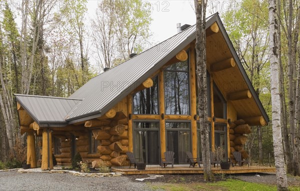 Luxurious Scandinavian style log home facade with large panoramic windows in spring, Quebec, Canada, North America