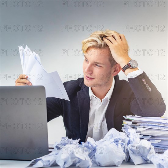 A man in a suit exhausted from work with papers and laptop, symbol bureaucracy, AI generated, AI generated