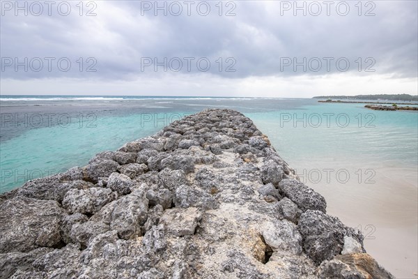 Caribbean dream beach with palm trees, white sandy beach and turquoise-coloured, crystal-clear water in the sea. Shallow bay on a cloudy day. Plage de Sainte Anne, Grande Terre, Guadeloupe, French Antilles, North America